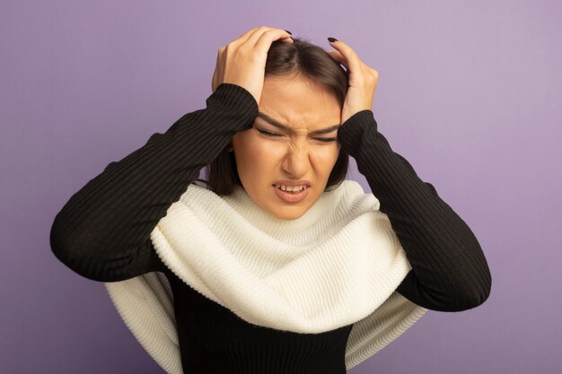 Young woman with white scarf touching her head looking unwell suffering from headache 