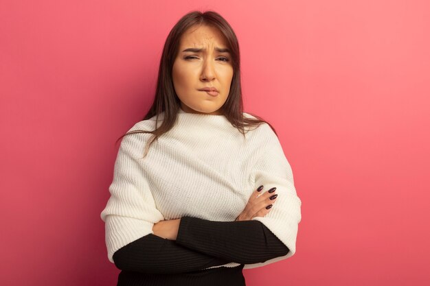 Young woman with white scarf with arms crossed on chest being displeased biting lip 