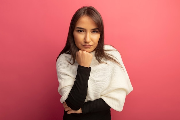 Young woman with white scarf with hand on chin with serious face thinking 