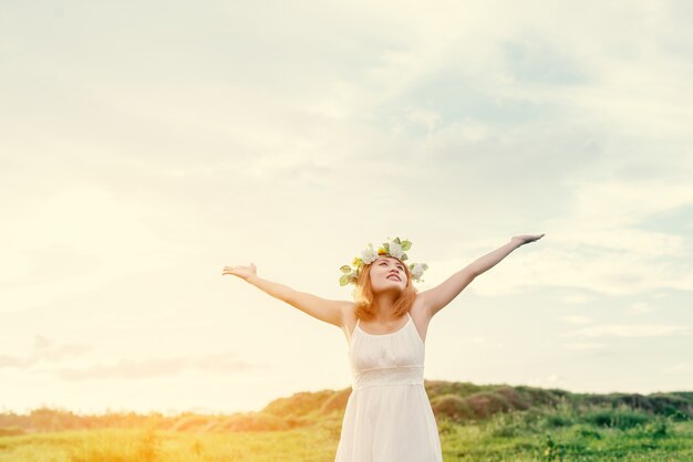 Young woman with wreath feeling alive outdoors
