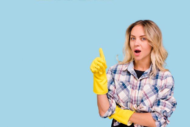 Young woman with yellow glove showing thumb up gesture looking at camera
