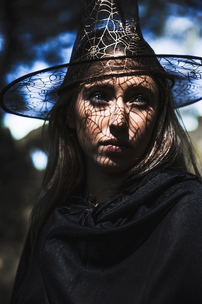 Free photo young woman in wizard costume looking away in forest