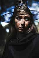 Free photo young woman in wizard costume looking away in forest