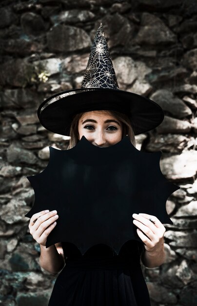 Молодая женщина в шляпе мастера закрыть рот с Хэллоуин украшения