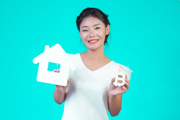 The young woman wore a white long-sleeved shirt with floral pattern, holding the house symbol and holding a currency symbol with a blue .