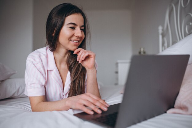 Young woman working on computer in bed