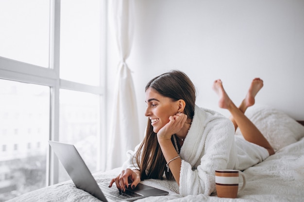 Young woman working on computer in bed