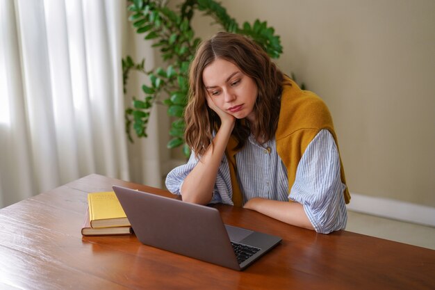 Young woman working at freelance home office feels tired after work