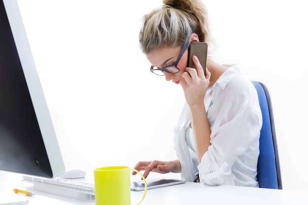 Бесплатное фото Молодая женщина, работающая из дома на компьютере и разговаривая по телефону с офисом