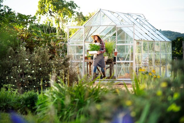 Young woman working at a glass greenhouse