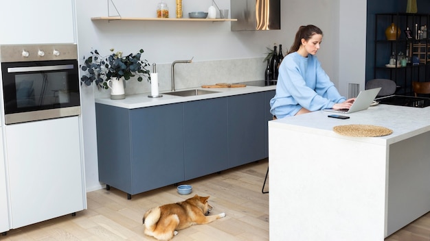 Free photo young woman working on her laptop next to her dog