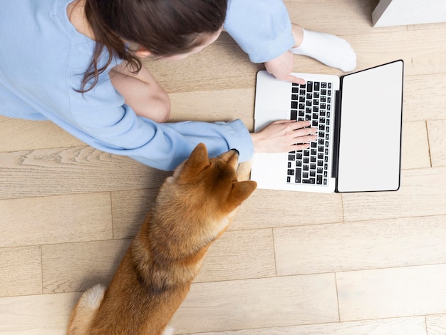 그녀의 강아지 옆에있는 그녀의 노트북에서 일하는 젊은 여자