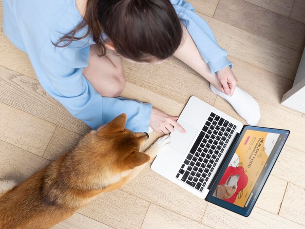 Young woman working on her laptop next to her dog