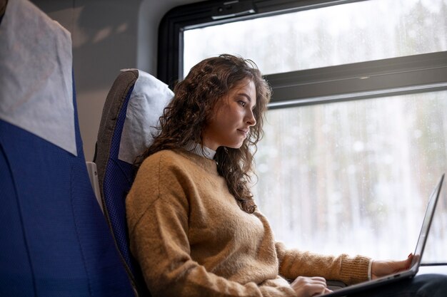 電車で旅行中に彼女のラップトップに取り組んでいる若い女性