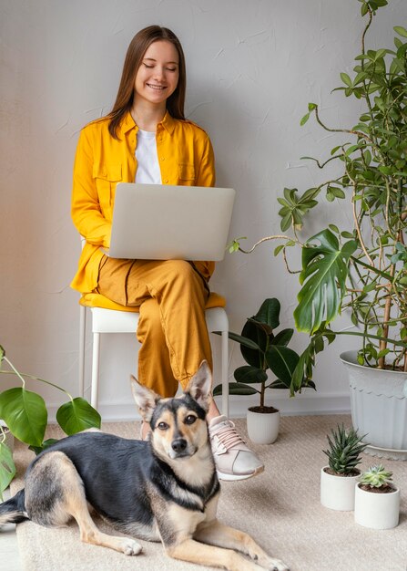 無料写真 彼女の犬の隣の彼女の家の庭で働く若い女性