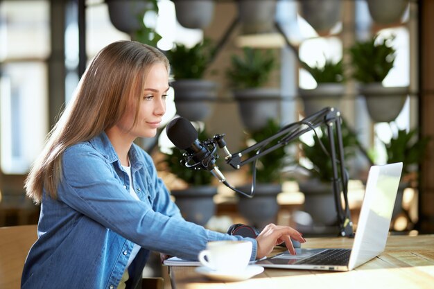 Young woman working in laptop with modern microphone