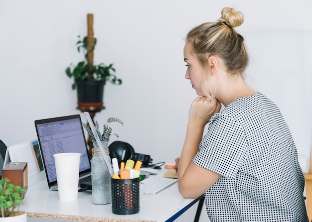 Giovane donna che lavora al computer portatile sul posto di lavoro