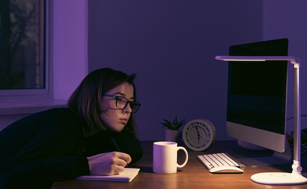 A young woman working at night in the workplace