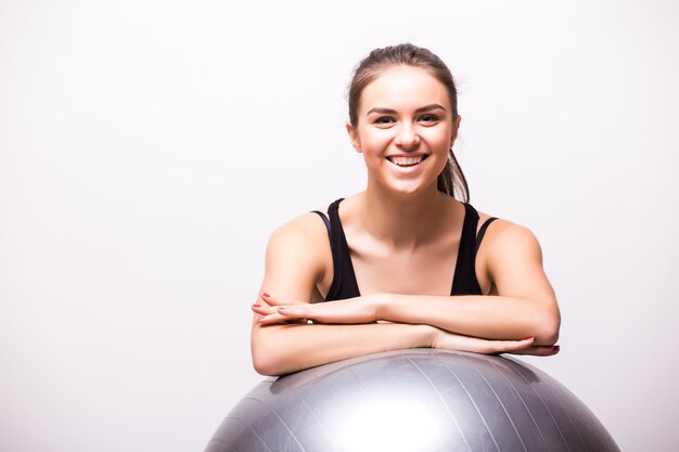 Young woman working out with a ball isolated on a white wall