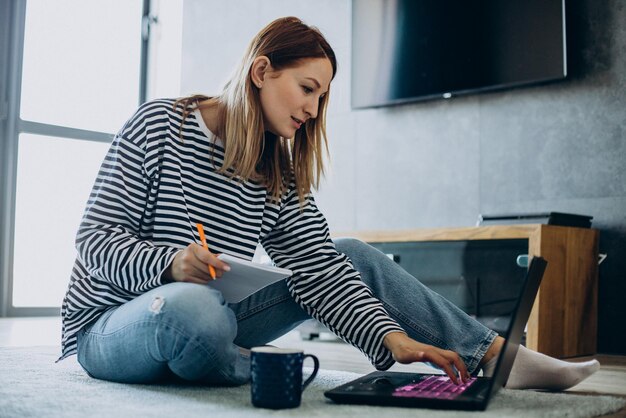 自宅からラップトップで働いて勉強している若い女性