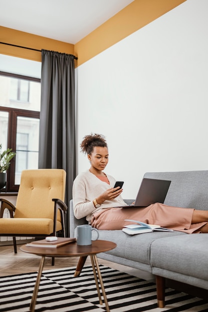 Free photo young woman working while sitting on the sofa