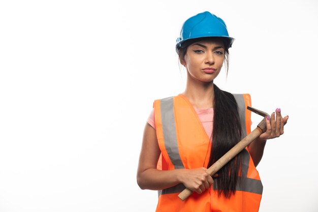 Young woman working with hammer on white wall 