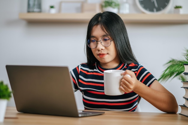 Una giovane donna che lavora con un computer portatile sul tavolo.