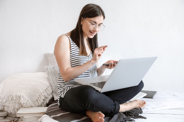 Una giovane donna lavora in remoto al computer di casa. libero professionista e lavoro su internet.