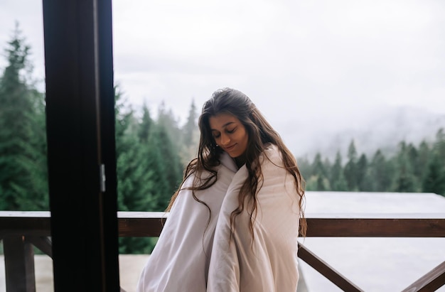 Free photo young woman wrapped in a blanket on the balcony