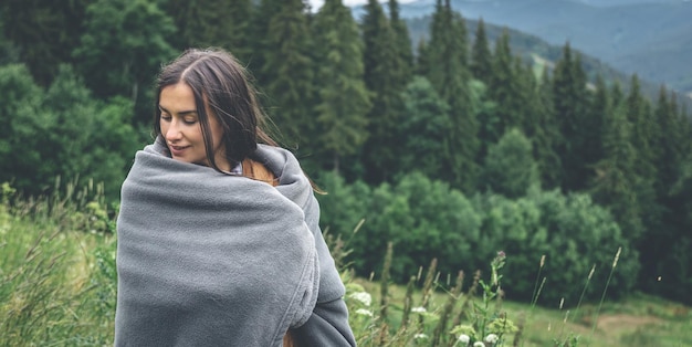 A young woman wrapped in a blanket in the mountains