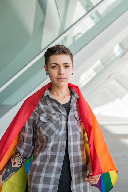 Foto gratuita giovane donna avvolta nella bandiera arcobaleno