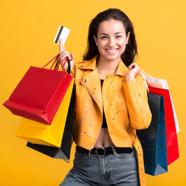 Free photo young woman in yellow leather jacket holding a card