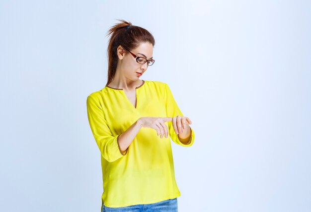 Young woman in yellow shirt checking her time