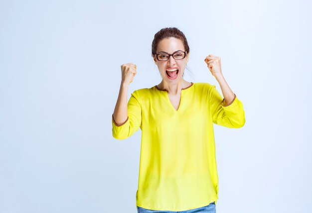 Young woman in yellow shirt feeling powerful and motivated