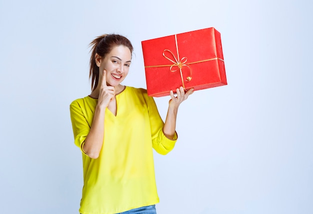 Young woman in yellow shirt holding a red gift box given at valentine day