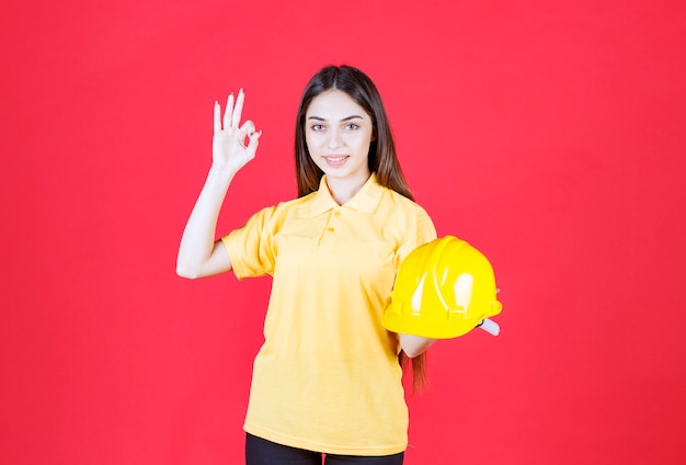 Young woman in yellow shirt holding a yellow helmet and enjoying the product