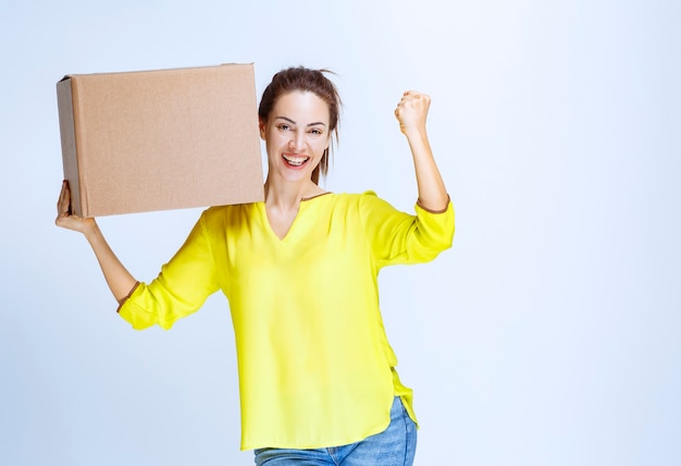 Free photo young woman in yellow shirt received her cargo and showing enjoyment sign