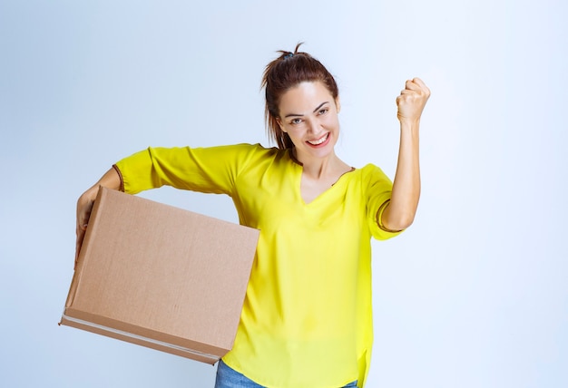 Young woman in yellow shirt received her cargo and showing enjoyment sign