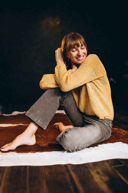 Free photo young woman in yellow sweater in her bedroom