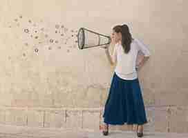 Free photo young woman yells into a megaphone drawn on the wall