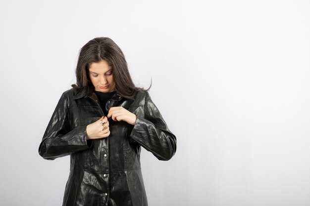 Young woman zipping black coat .