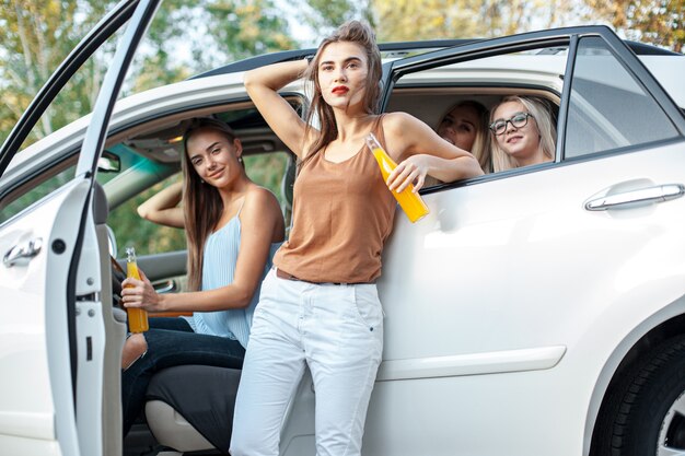 Молодые женщины в машине улыбаются и пьют сок