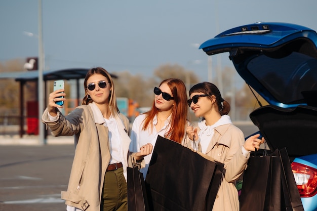 Foto gratuita giovani donne in macchina con le borse della spesa che fanno un selfi