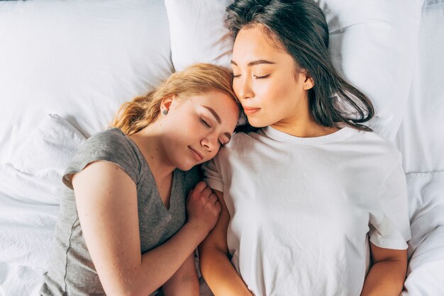 Молодые женщины обнимаются спать в постели