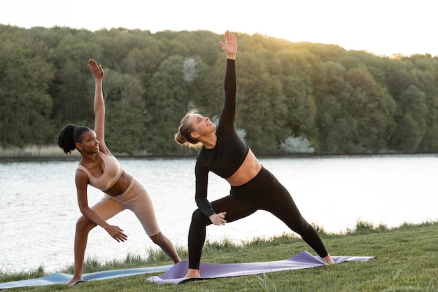 Foto gratuita giovani donne che fanno fitness insieme all'aperto