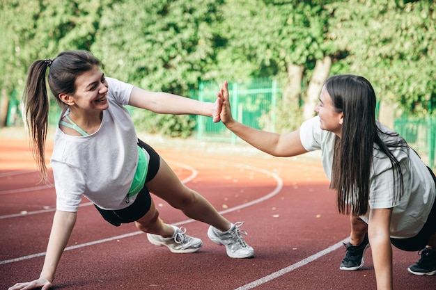 Free photo young women doing stretching exercises at the stadium