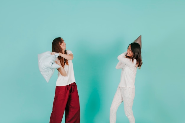 Young women fighting with pillows