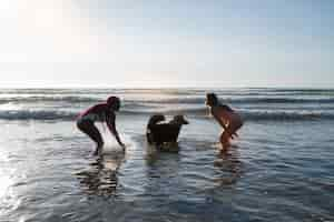 Foto gratuita giovani donne che si divertono con il cane in spiaggia