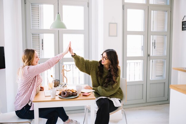 Young women high-fiving over table
