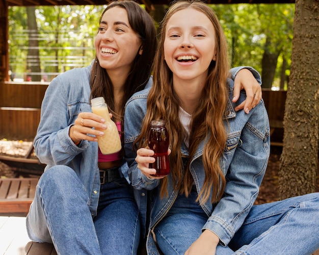 Young women holding fresh juice bottles and laughing